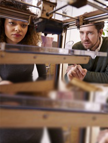 Une femme et un homme regardent une imprimante 3D